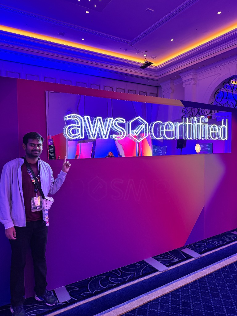Harsh Akshit at AWS re:Invent conference with AWS Certified sign